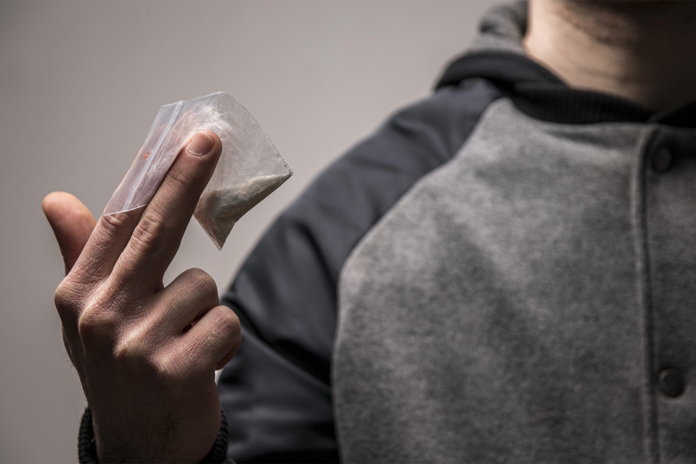A person holding a small bag containing an unidentified white substance