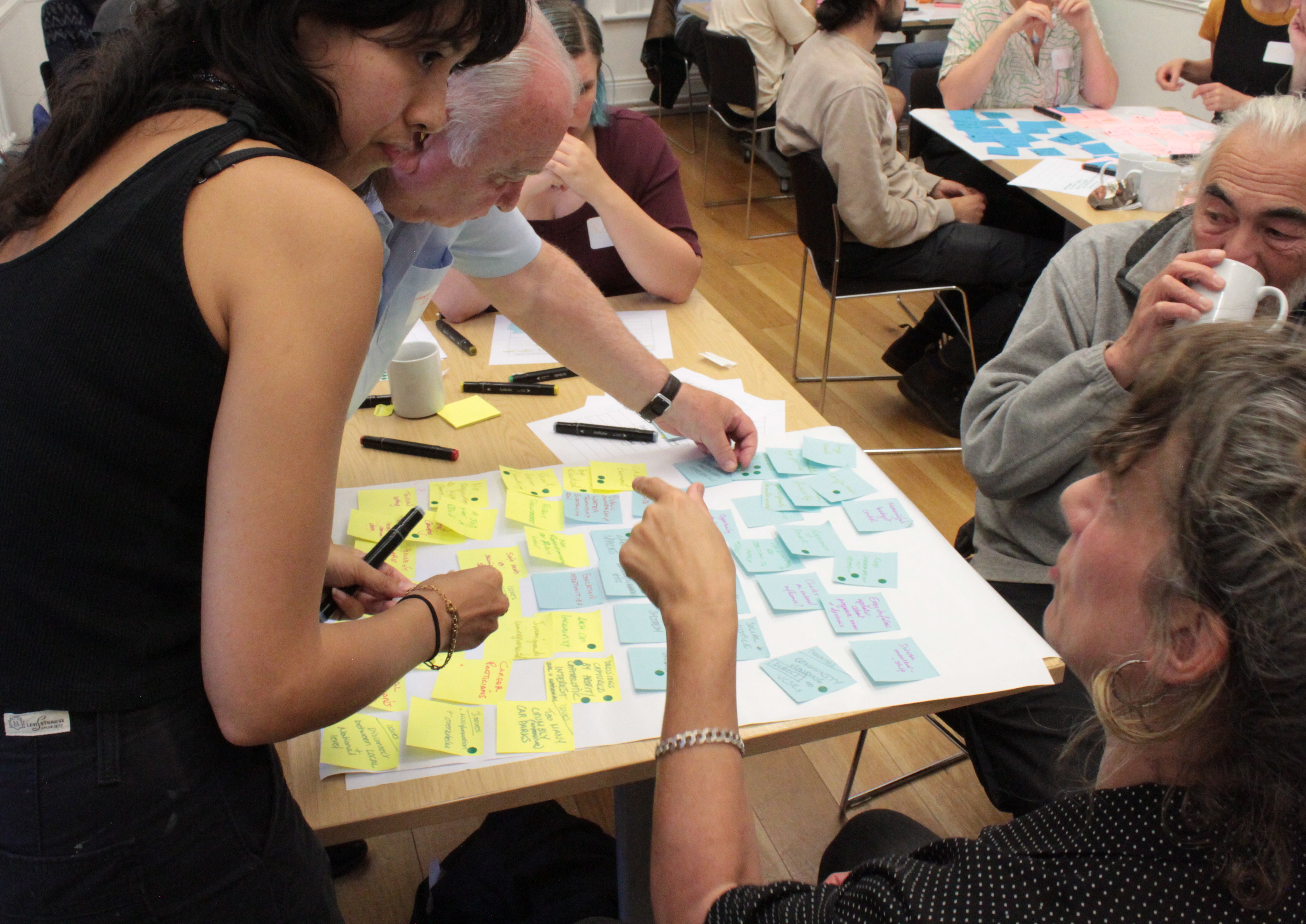 A group of people work around a table covered in postit notes
