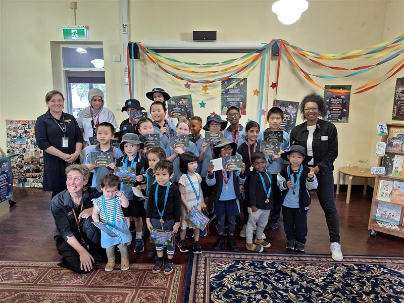 Photo of Trina with a group of children and library staff at Kurilpa Library