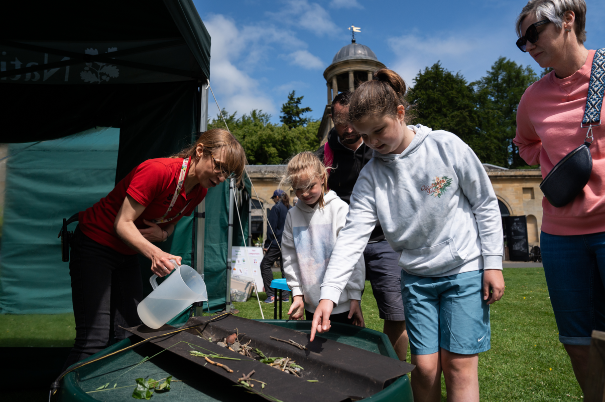 Children and adults taking part in a hands-on nature activity at an outdoor community event.