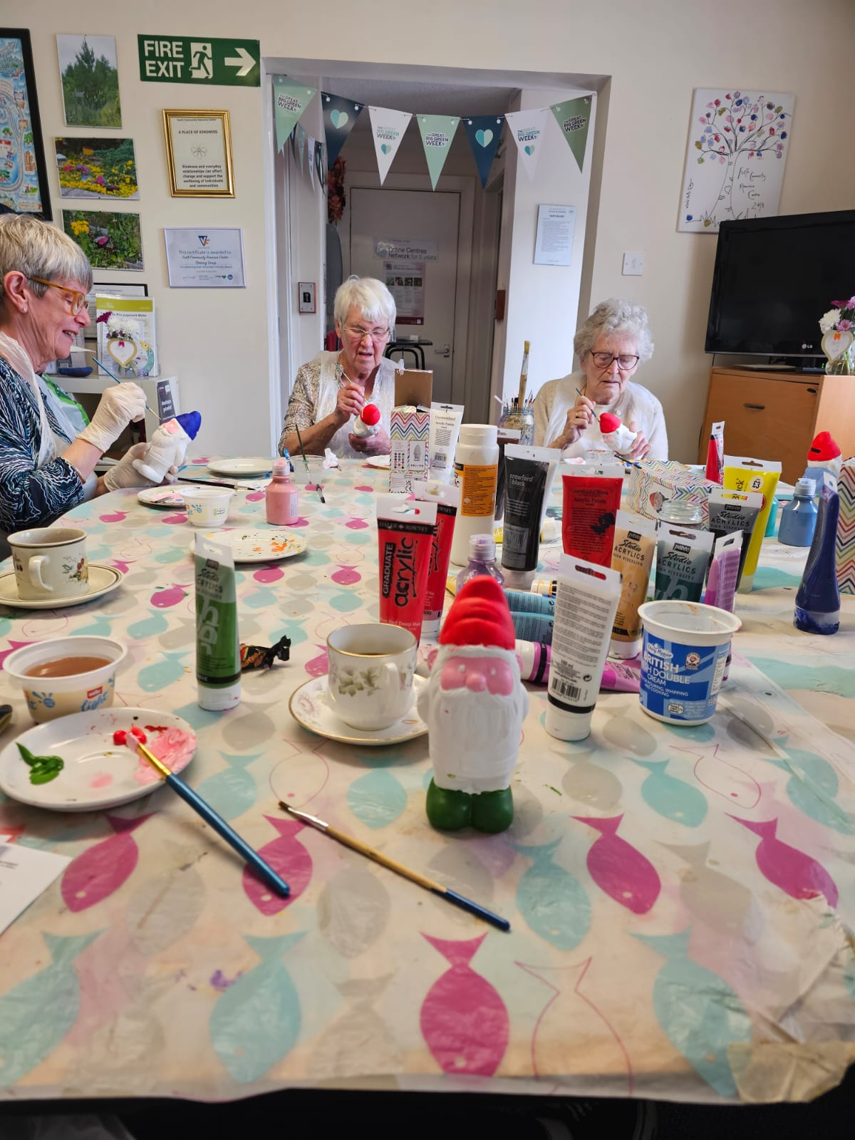 A group of people sit round a table and begin painting garden gnomes
