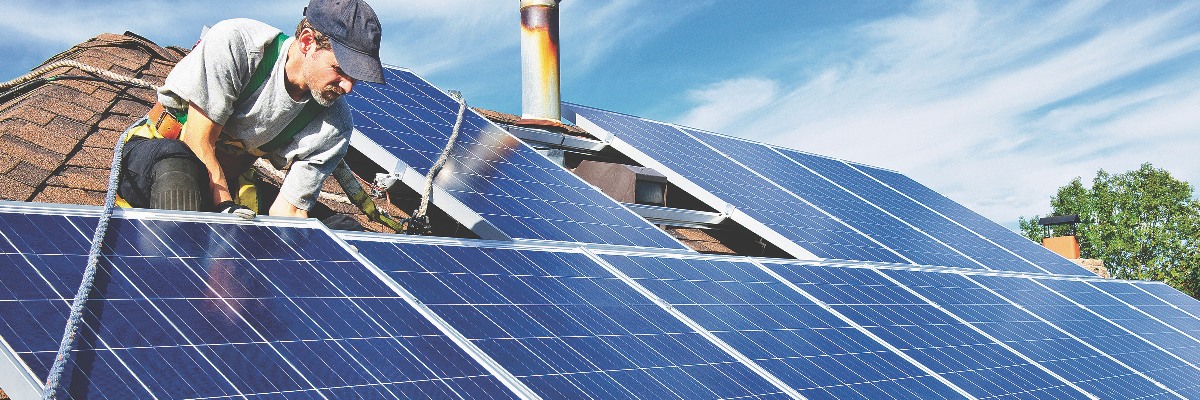 A worker fitting solar panels on a roof.