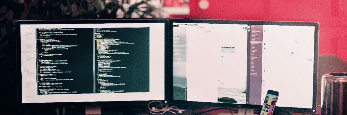 Two computer screens at a desk.