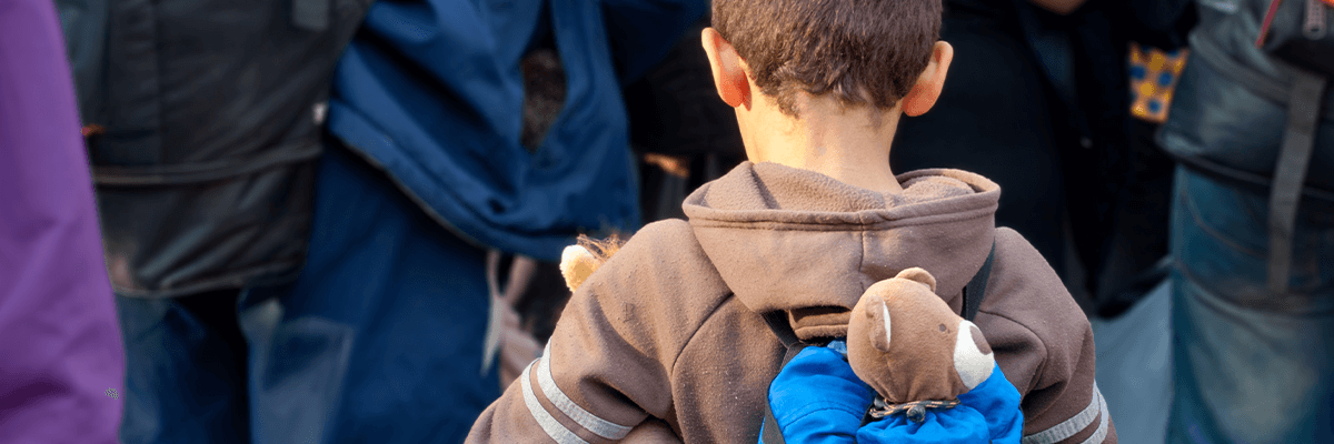 A child refugee with teddy bear in backpack
