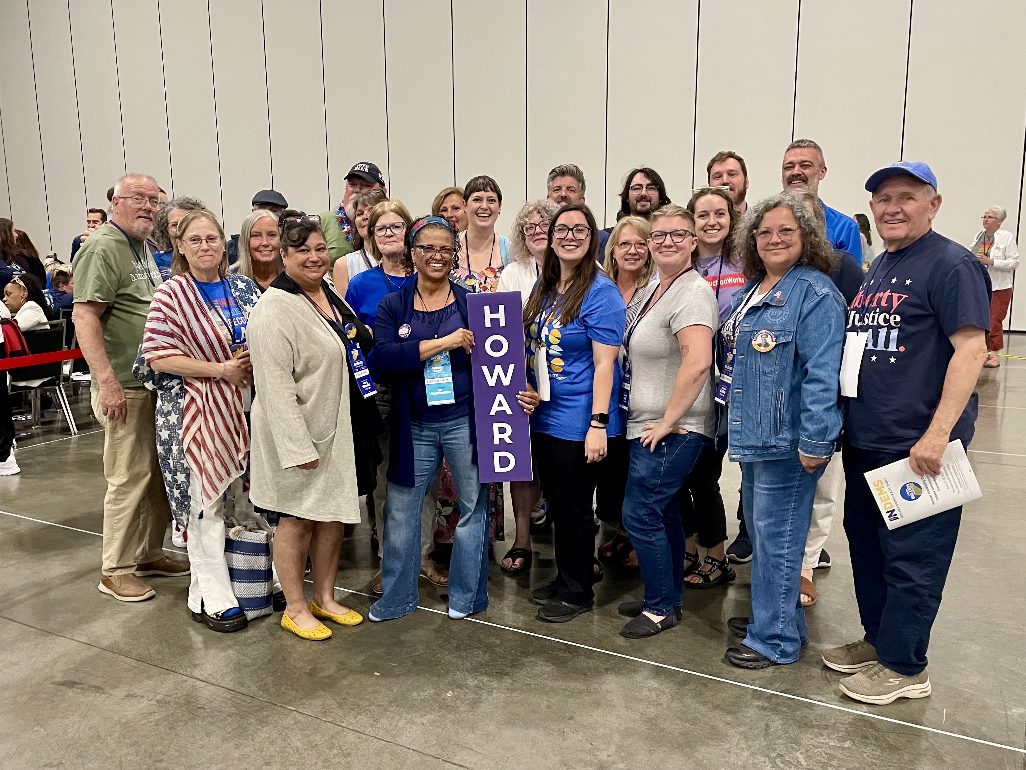 The Howard County delegation gathered on the convention floor, holding a vertical HOWARD county sign.