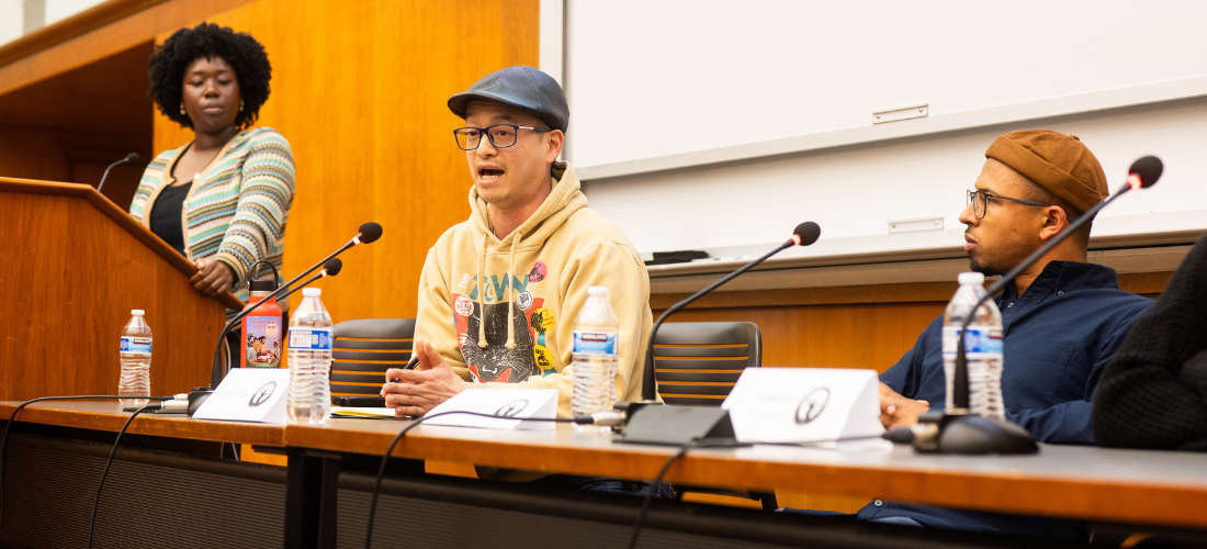 Veryl leaning over microphone, sitting on a panel