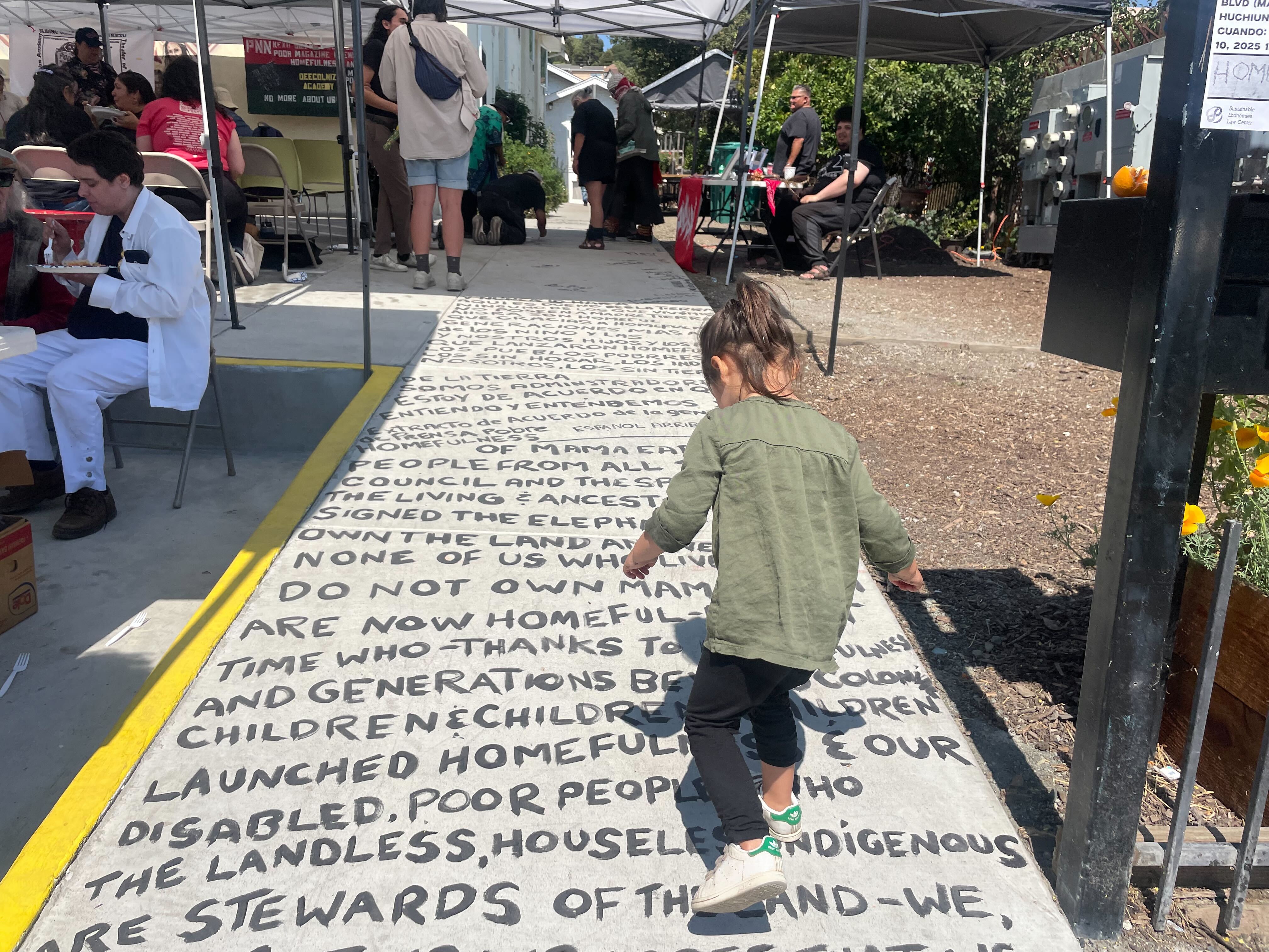 A young child steps on words painted on a walk way