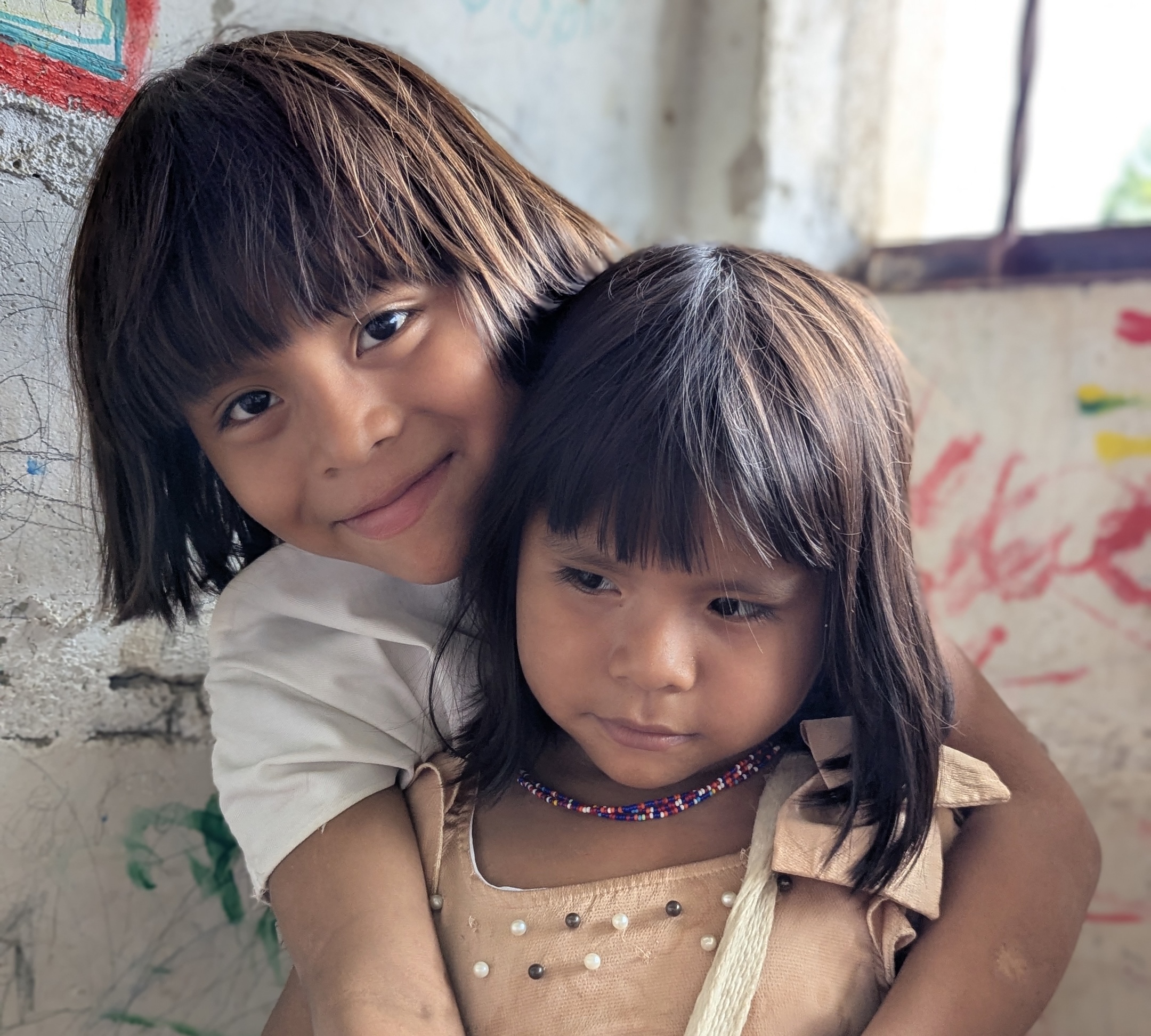 Two Arhuaco indigenous children from Colombia's Sierra Nevada mountains, one wearing traditional beaded choker necklace
