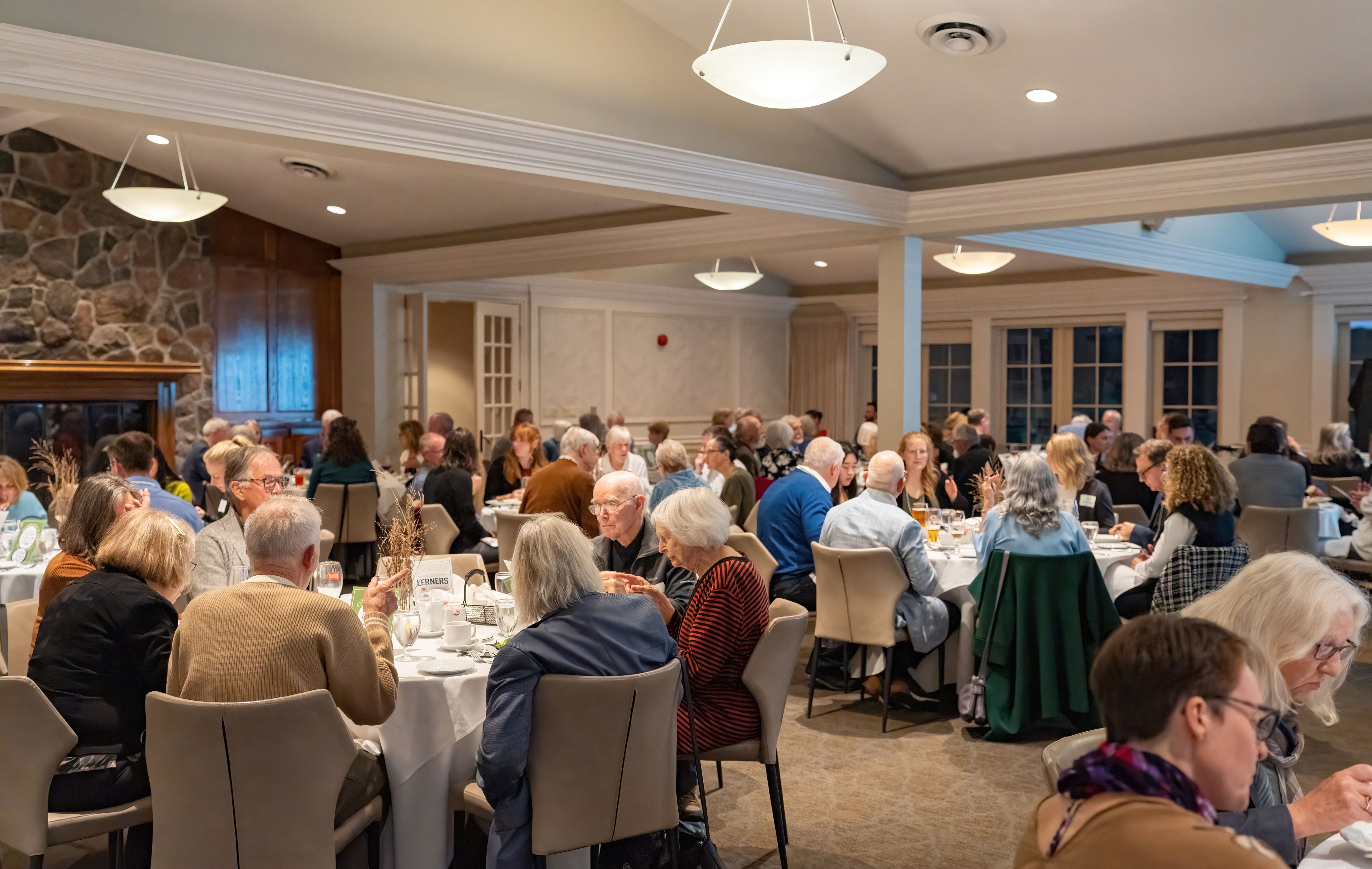 A room full of people sitting at multiple round tables in a large dining room