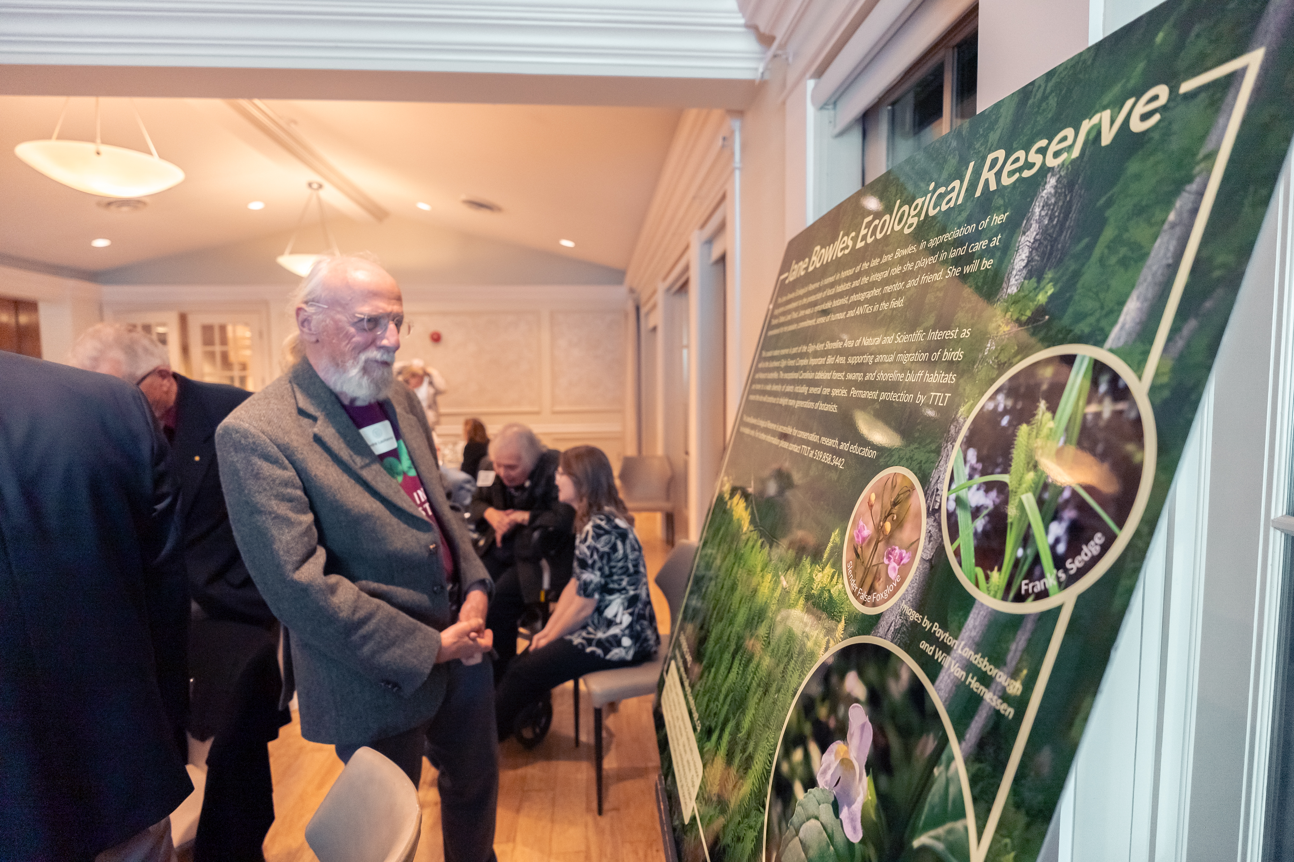 A man with white hair looking at a large nature reserve sign