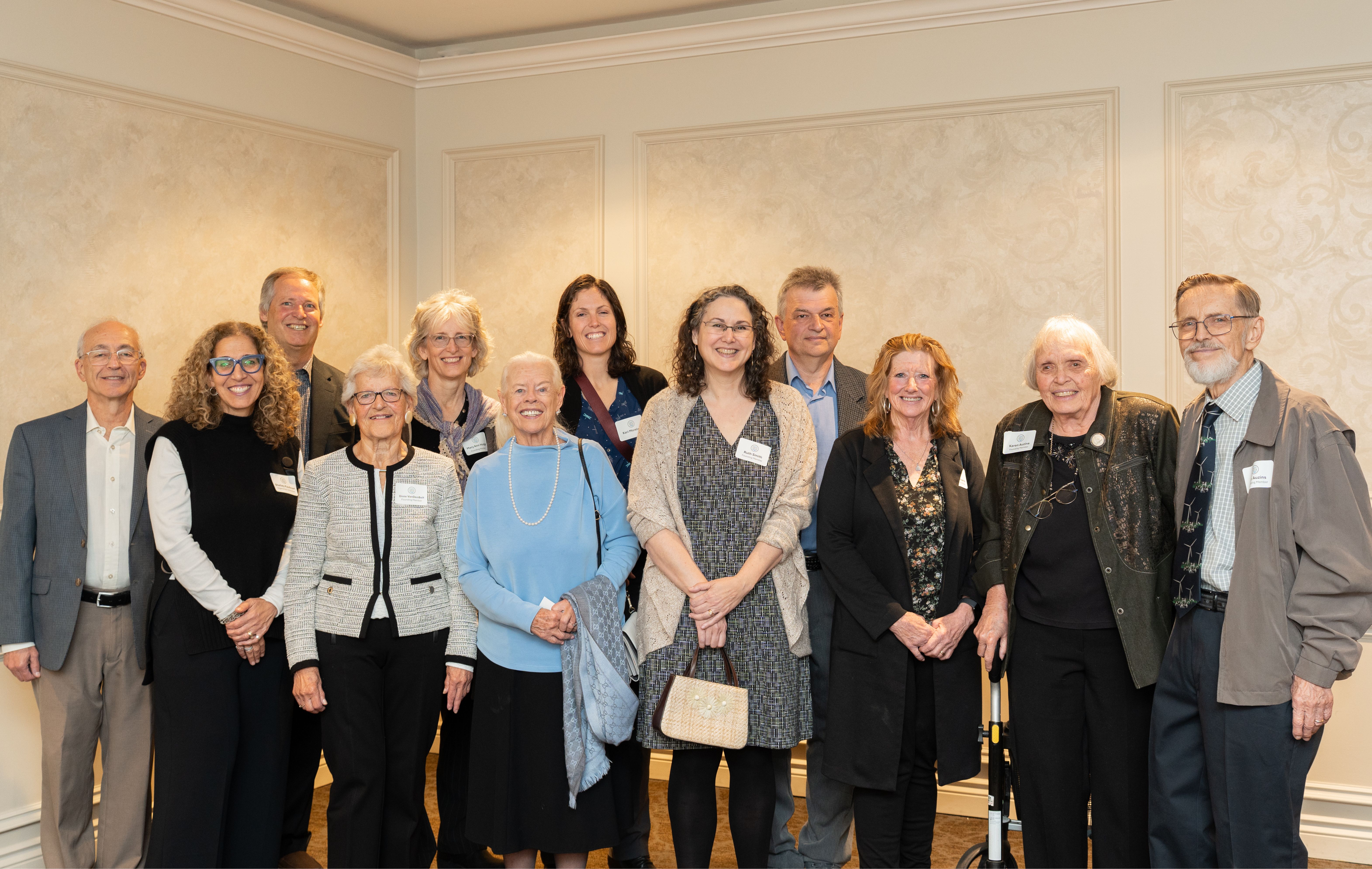 A group of people, mostly older than 60, standing in two lines posing for the camera