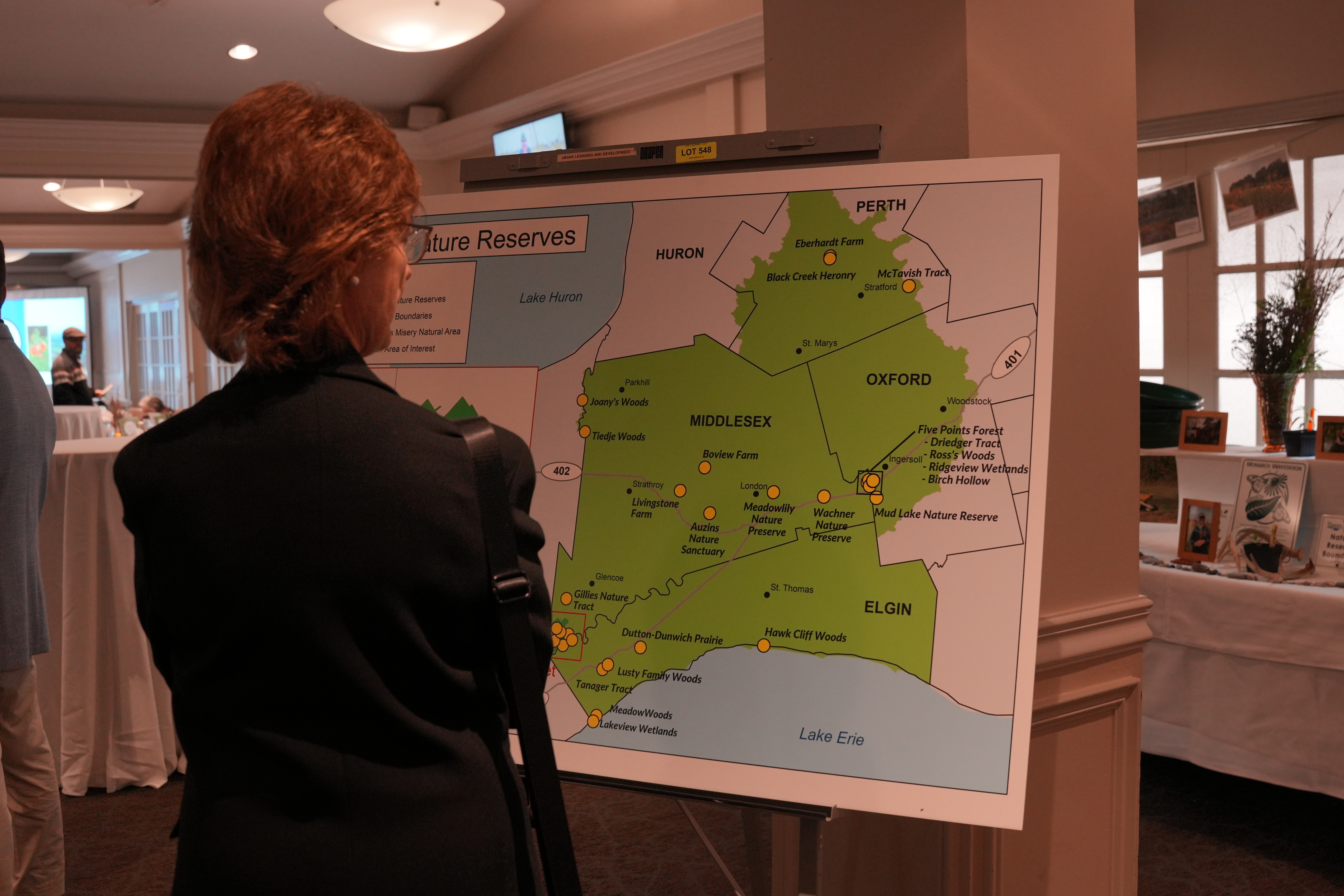 A woman looking at a large printed map of Perth, Middlesex, Oxford, and Elgin counties showing where nature reserves are