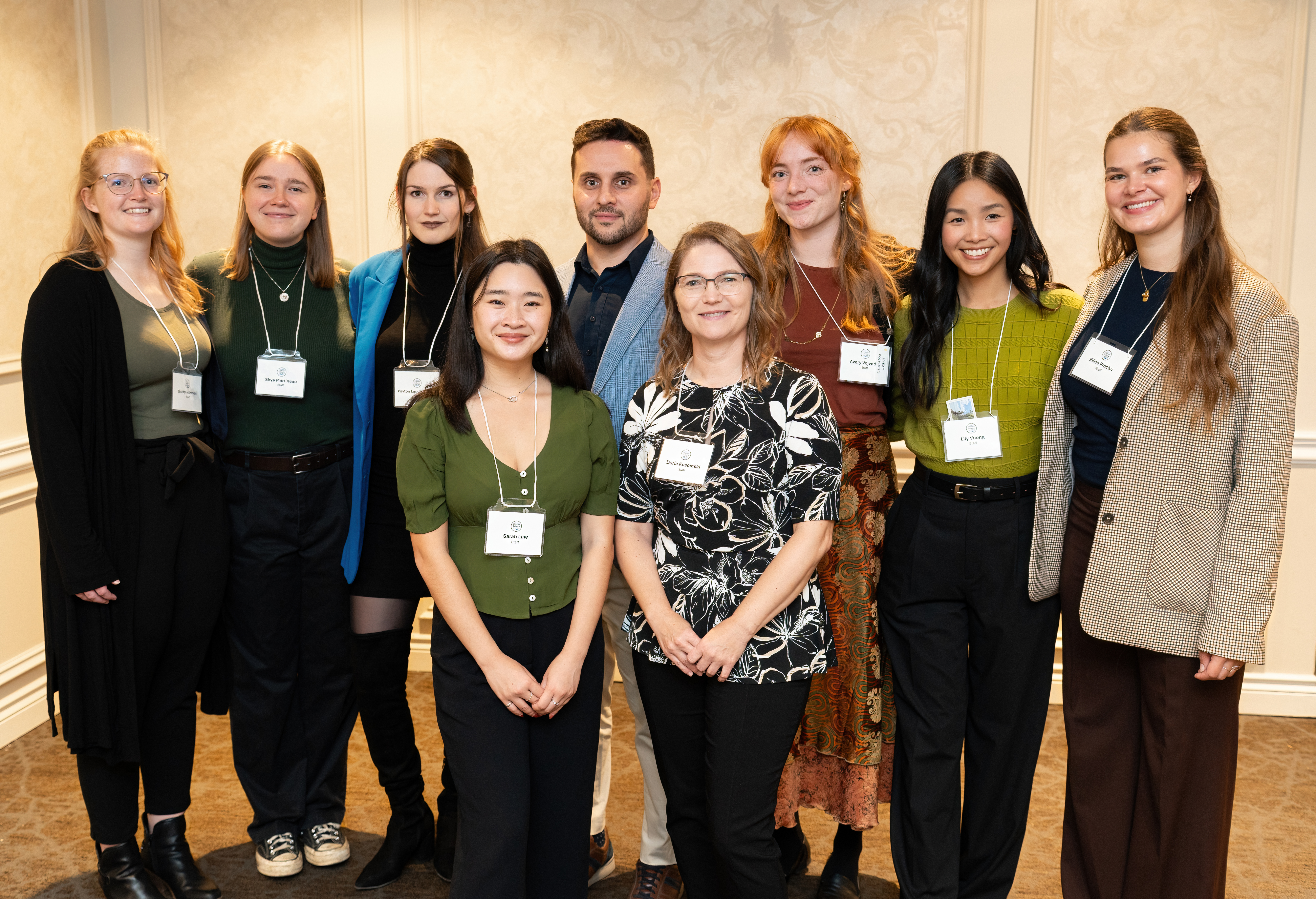 Group of several young women and one man standing in two rows posing for a photo