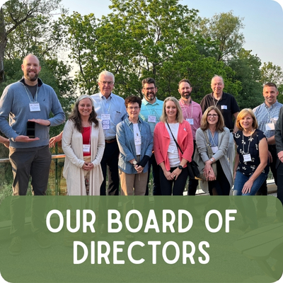 A collection of men and women stand in two rows, facing and smiling at the camera/