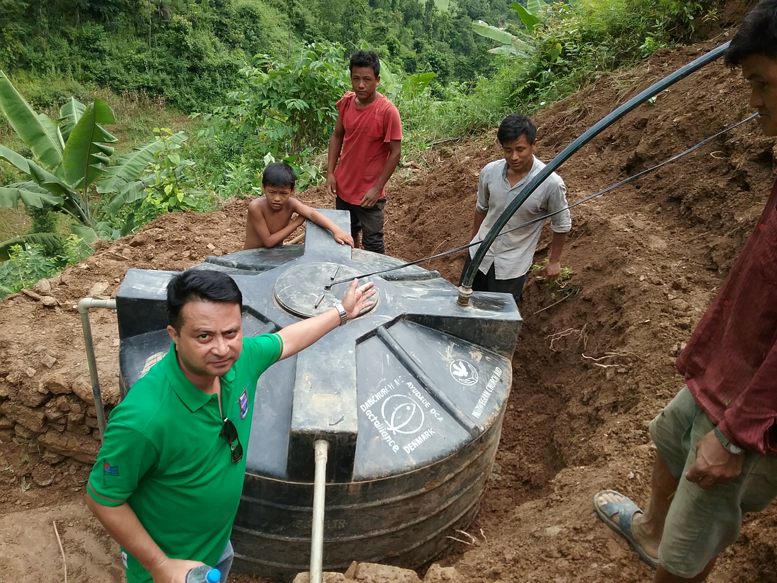 In Nepal's Dhading District, community members complete installation of their new water catchment tank, to collect water from the spring below their village.
