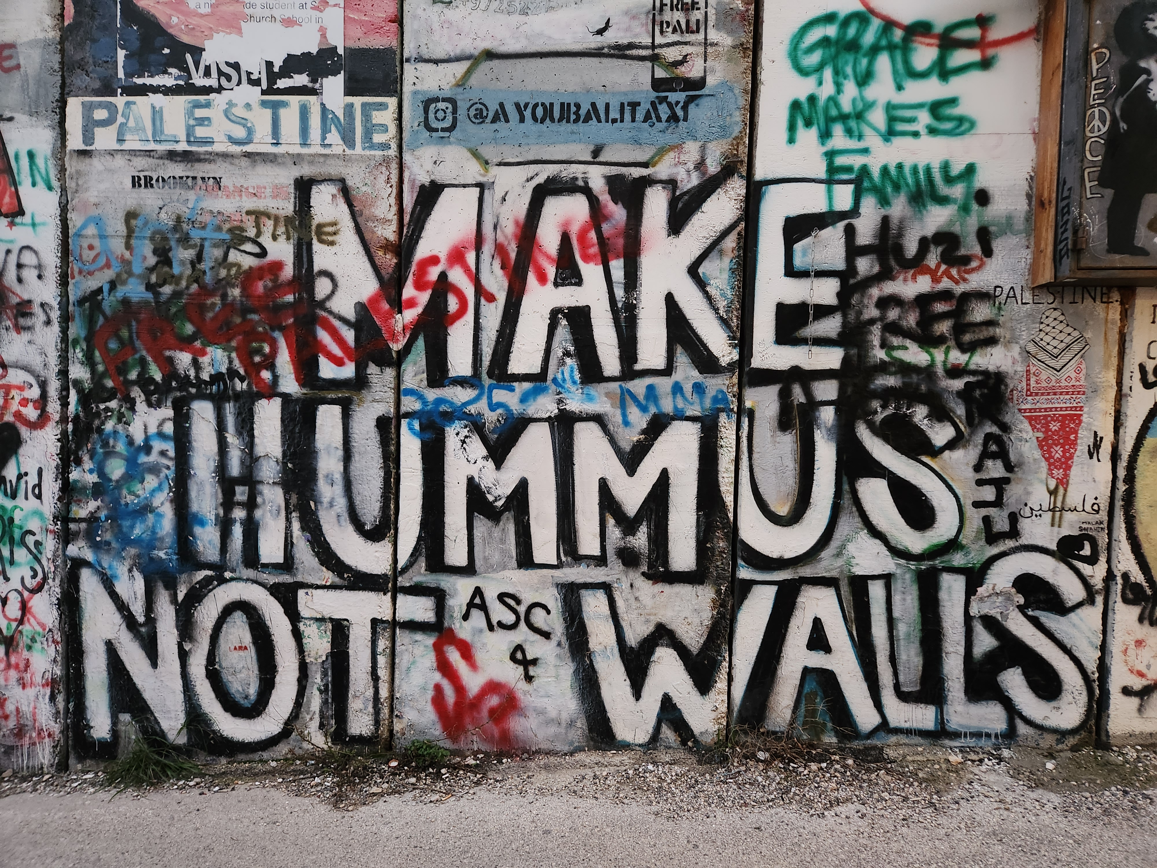 Concrete separation wall in West Bank, prominent phrase Make Hummus Not War.