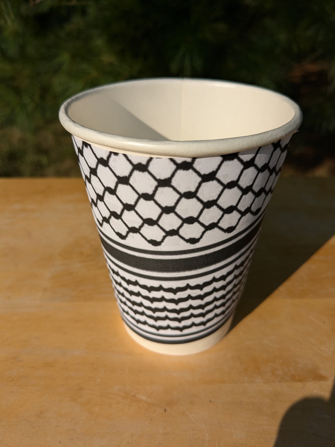 paper cup decorated with a Palestinian keffiyeh pattern