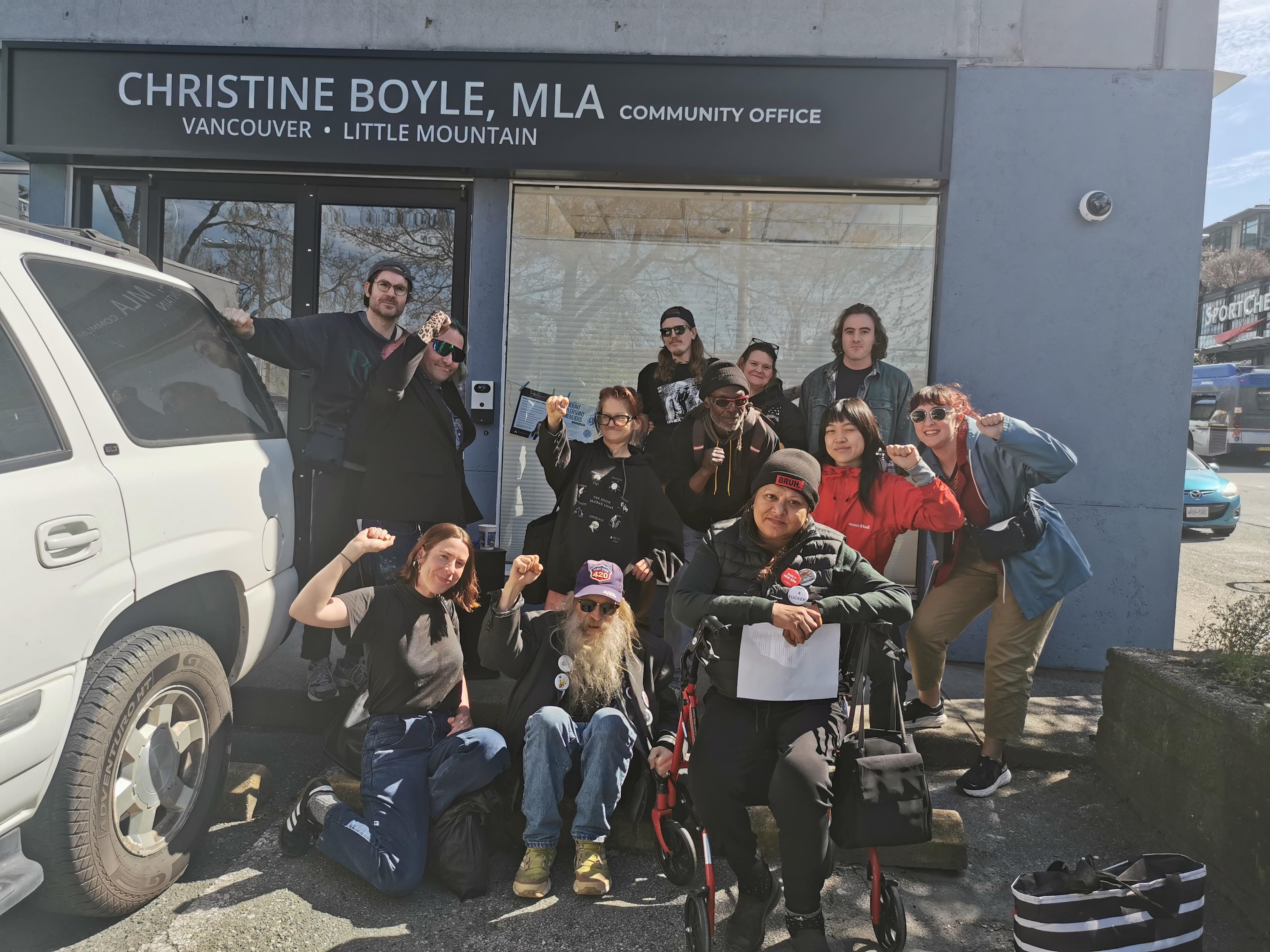 A group of people pose in front of Christine Boyle's MLA office with fists up
