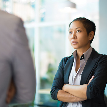 A woman stands cross armed looking at what is assumed to be the back of a man giving her a hard time
