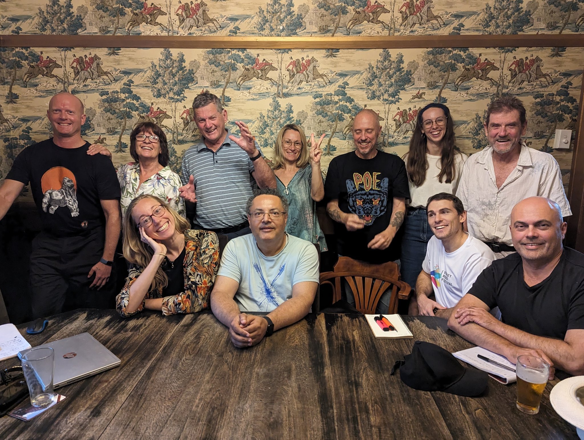 a dozen people indoors sitting and standing in a group around a table