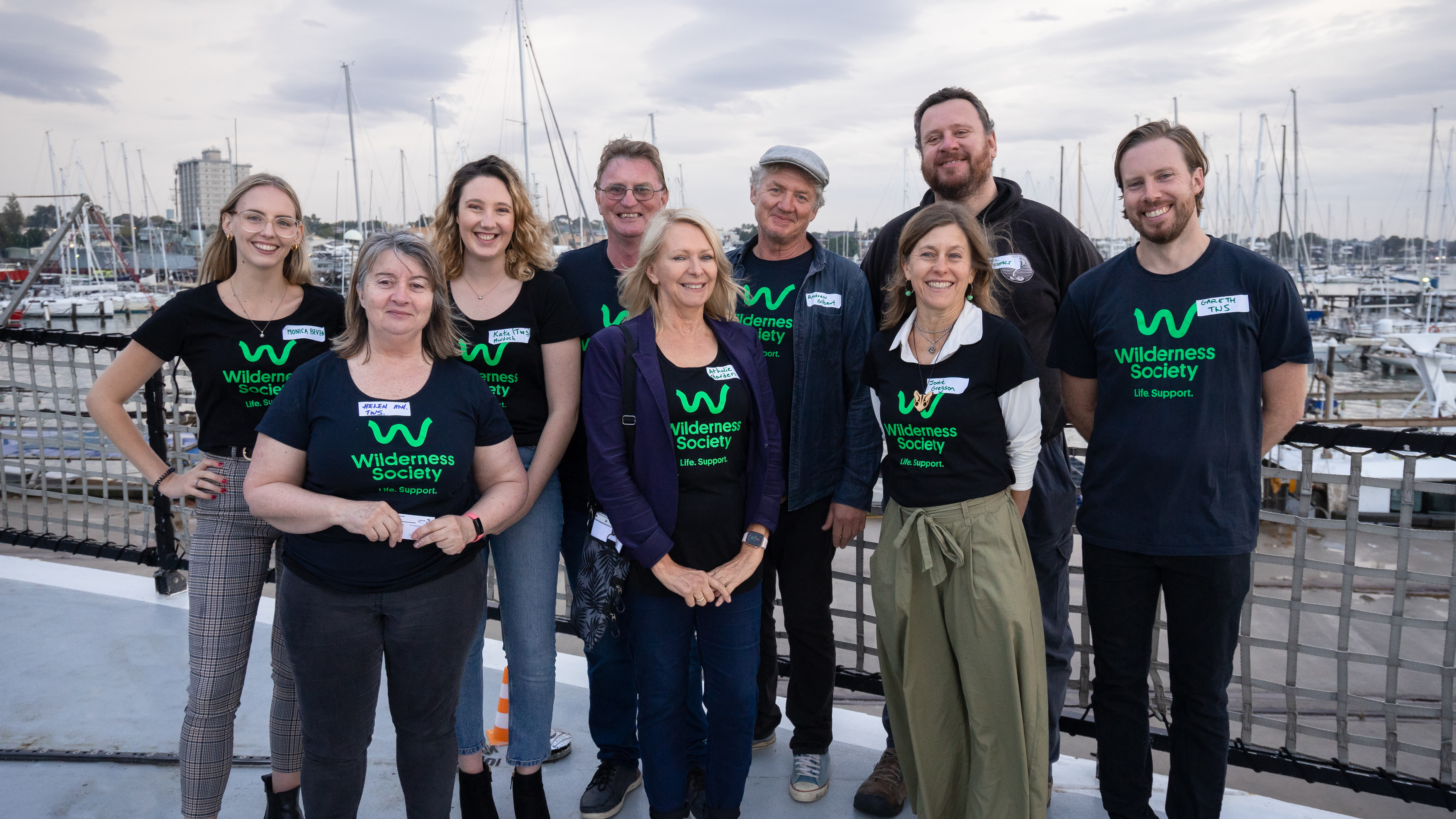 The Westside group wearing Wilderness Society shirts smiling on a pier. 