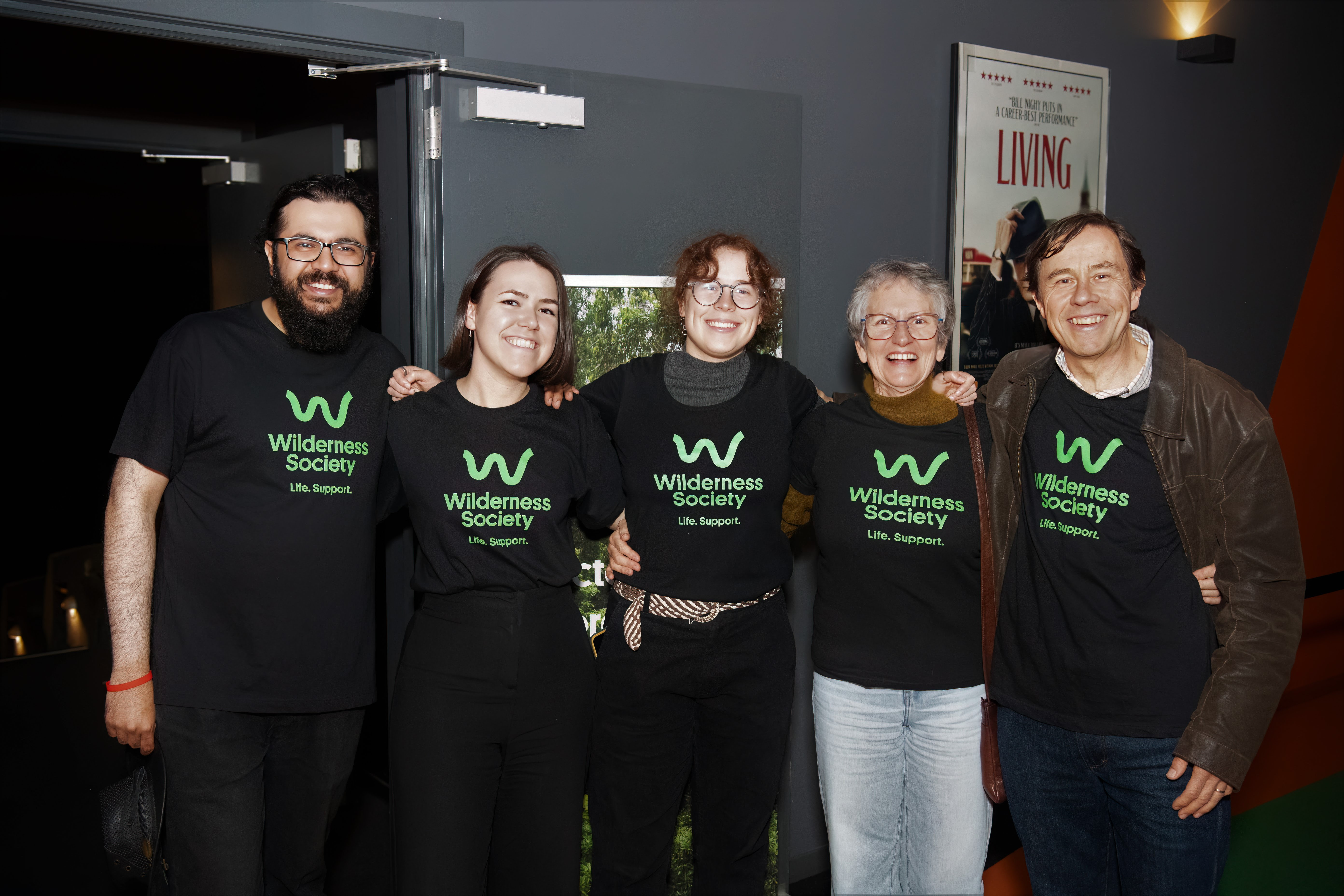 Five East Group members smiling in Wilderness Society shirts at Lido Cinemas, Hawthorn. 