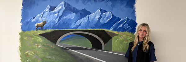 Kylie by her mural A woman stands in front of a mural of a wildlife crossing