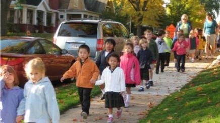 A group of elementary aged kids walking on the sidewalk.
